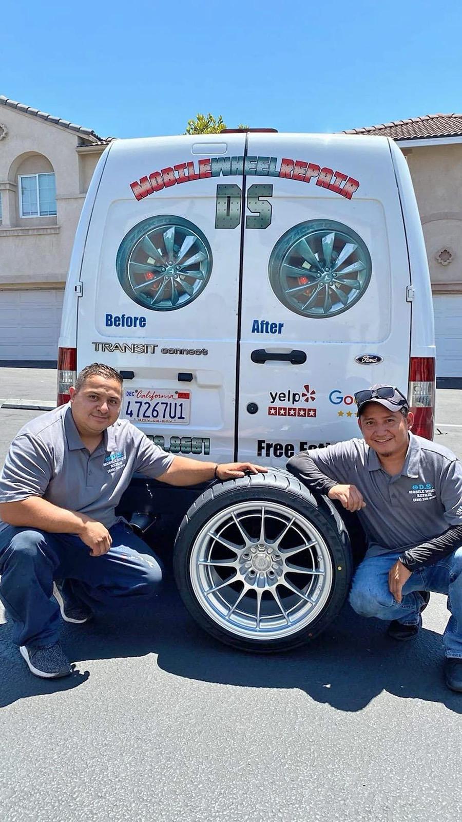 D S Mobile Wheel Repair technicians kneeling beside a repaired wheel behind their branded van